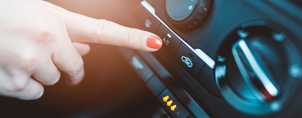 Woman turning on air conditioning in car